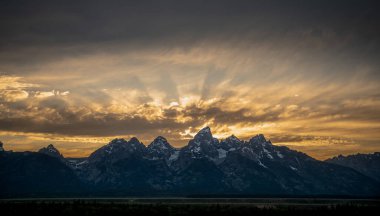 Yaz başında gün batımında Grand Teton Sıradağları üzerinde güneş ışınları patladı