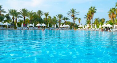Güzel tropikal plaj ve deniz şemsiyesi ve sandalyesi otel tatil ve tatil için yüzme havuzunda.