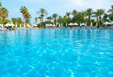 Güzel tropikal plaj ve deniz şemsiyesi ve sandalyesi otel tatil ve tatil için yüzme havuzunda.