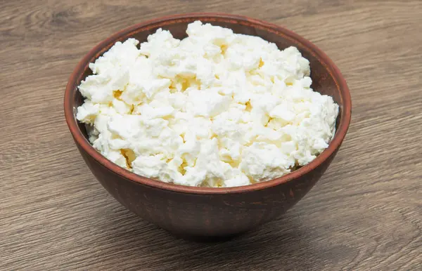 Ahşap masanın üstündeki kasede süzme peynir.