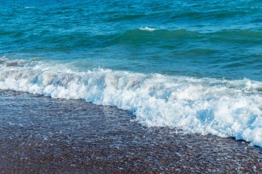 Kumlu sahilde yumuşak bir mavi deniz dalgası.