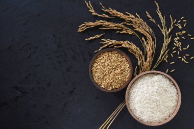 Siyah arka plana yerleştirilmiş sepetlerde çeltik ve pirinç.