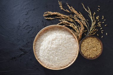 Siyah arka plana yerleştirilmiş sepetlerde çeltik ve pirinç.