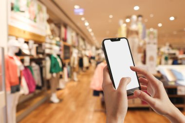 Woman holding mobile phone pressing payment for online shopping against blurred background of department stores. Online shopping concepts.