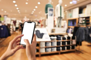 Woman holding mobile phone pressing payment for online shopping against blurred background of department stores. Online shopping concepts.