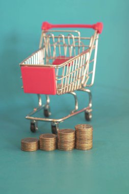 Mavi arka planda alışveriş arabasındaki altın sikkeler