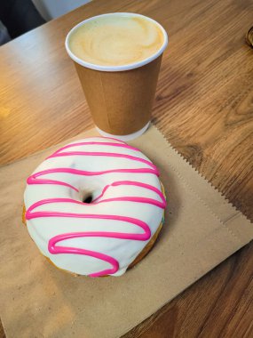 Beyaz ve pembe kremalı çörek ve masaya bir fincan kahve..