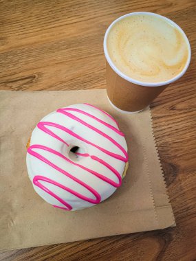 Beyaz ve pembe kremalı çörek ve masaya bir fincan kahve..