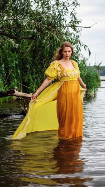 水の中に立つ黄色の歴史的なドレスでブロンドの女性の映画館 — ストック動画