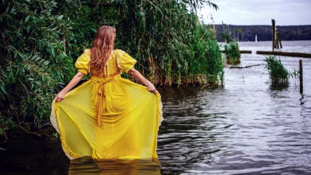 水の中に立つ黄色の歴史的なドレスでブロンドの女性の映画館 — ストック動画