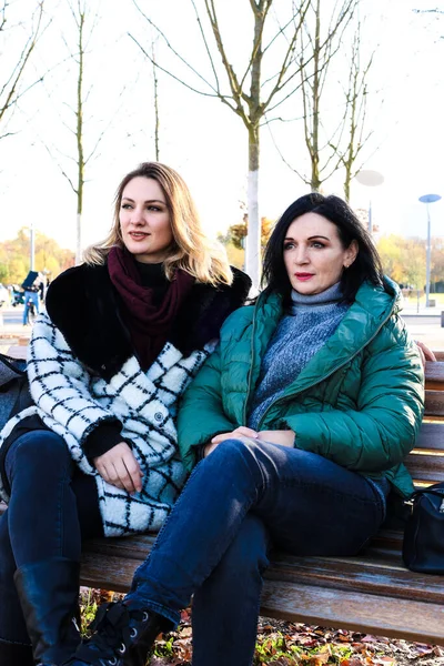 Портрет Двух Женщин Сидящих Снаружи Скамейке Пальто — стоковое фото
