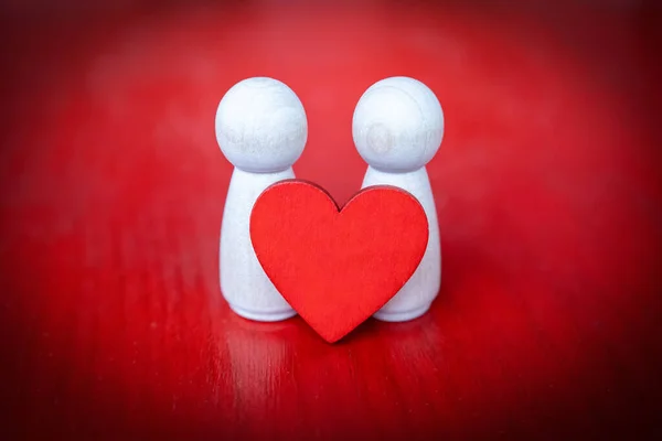 Δύο Ξύλινες Φιγούρες Κρατώντας Μια Κόκκινη Καρδιά Κόκκινο Φόντο — Φωτογραφία Αρχείου