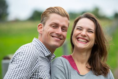 Doğada gülen genç bir çiftin portresi.