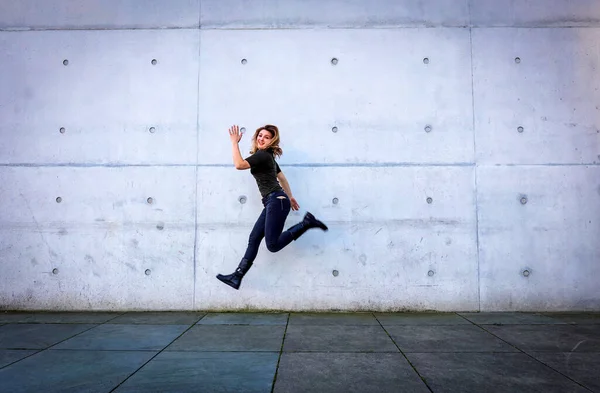 Mujer Joven Ropa Negra Saltando Frente Pared Gris Imagen de archivo