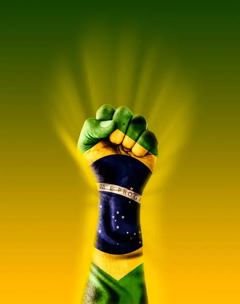 Üzerinde Brezilya bayrağı olan yumruk yeşil ve sarı arka planda parlak bir ışıkla aydınlatılır.