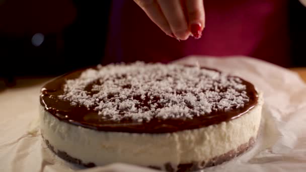 요리사의 손가락으로 초콜릿 디저트에 코코넛 조각을 뿌려서 서서히 디저트 준비를 — 비디오