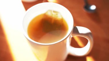 Beyaz fincanı sıcak yeşil çayla, görünür buharı çay kesesi ya da kupanın içinde sabah içeceği konseptiyle kapatın.