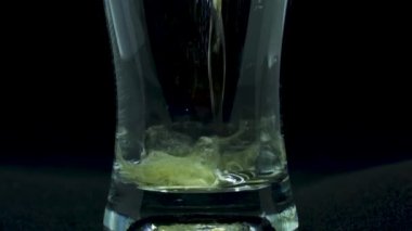 Serinletici bir bira bardağının yakınlaştırılmış makro çekimi. Alkolik sıvı temiz kadehi doldurur. Lager Malt meşrubat jeti konteynırın beyaz arka planına düşüyor. El yapımı bira fabrikası konsepti