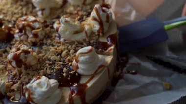 Close of a creamy cake made of mascarpone cheese with topping of whipped cream, caramel and nuts, delicious dessert being served on a plate