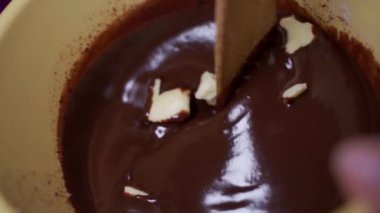 Slow motion footage of a wooden stick mixing butter in a hot melted chocolate