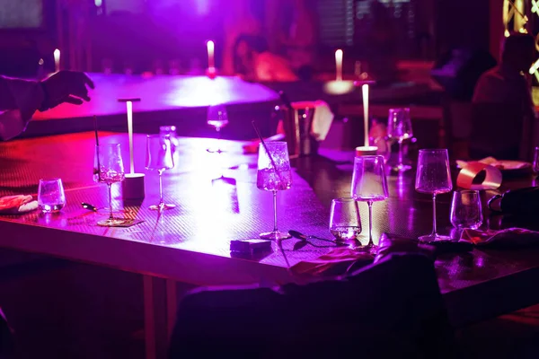 A table at a night party or celebration with empty glasses of alcohol such as wine