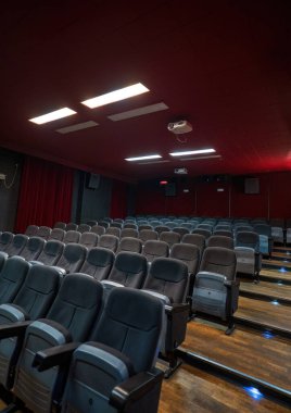 Tavanda projektör olan bir sinema salonunun içi boş sinema salonu koltukları, rahat ve yumuşak sandalyeler. Perspektif oditoryum görünümü.