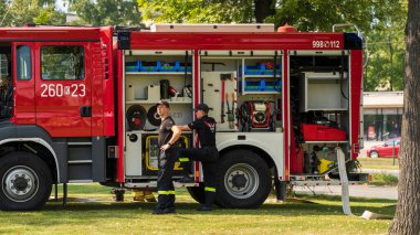 Krakow, Polonya - 01 Ağustos 2023: İtfaiye ekibi bir parkta çalışan iki adamı gösteriyor