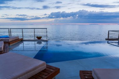 Su villası, teras manzarası şemsiyenin altında güneş yatağı koltukları, çarpıcı okyanus manzaralı lüks havuz oteli. Güzel spa ya da sağlık konsepti, tatil beldesi huzur alanı