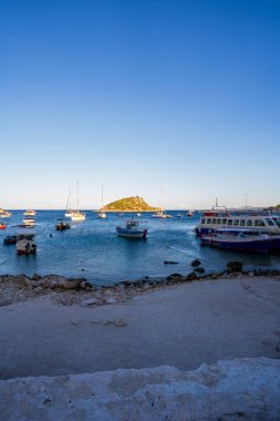 Yunanistan 'ın Zakynthos adalarından birinde mavi deniz ve dağa karşı park halindeki Agios Nikolaos limanındaki motorlu teknelerin panorama görüntüsü