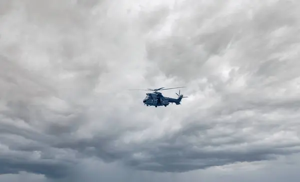 Stock image Spanish Air Force AS.332 Puma military combat search and rescue helicopter on the tarmac of Torrejon airbase flying above sea during cloud thunderstorm weather