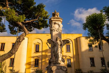 Sorrento, İtalya - 20 Haziran 2024: Güneşli bir günde yakalanan tarihi bir binanın önündeki zarif melek heykeli. Mors Ölümsüzlük Anıtı, Piazza della Vittoria