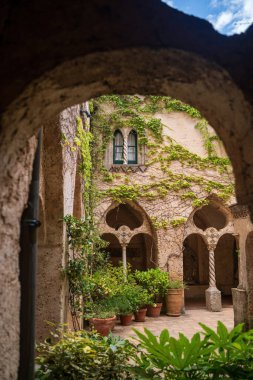 Ravello, İtalya - 20 Haziran 2024: Cimbrone villa manzaralı Charming Mediterranean avlusu, kemerli yürüyüş yolları, yemyeşil ve sarmaşık kaplı duvarlar, sakin ve tarihi bir ortam sunuyor.