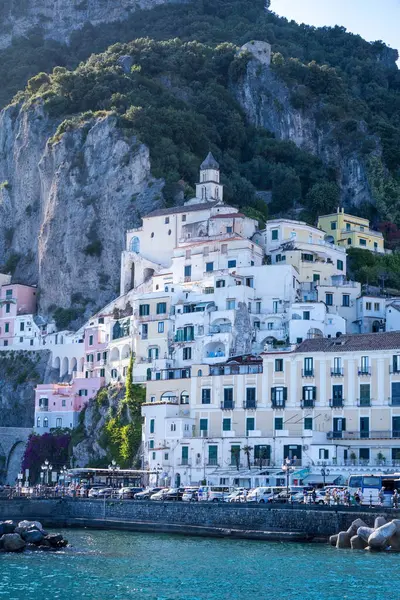 stock image Amalfi, Italy - June 24, 2024: Architecture of Amalfi's hillside buildings, nestled against the towering cliffs and lush greenery, showcasing the unique charm of Italy's Amalfi Coast.