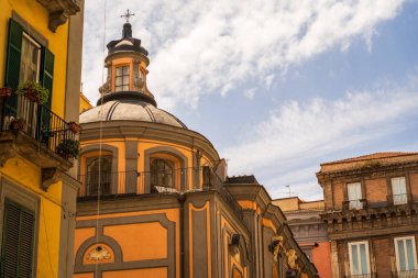 Napoli 'nin mimari cazibesinin güneşli bir görüntüsü, dingin gökyüzü altında canlı renkler ve klasik kubbeli yapılar sergiliyor.