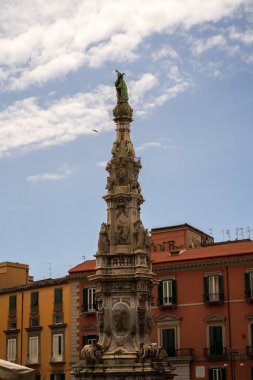 Napoli, İtalya - 22 Haziran 2024: Heykellerle süslenmiş görkemli bir dikilitaş Napoli, İtalya 'da canlı mavi gökyüzüne karşı karmaşık detaylar sergiliyor..