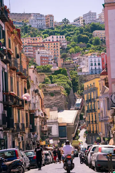 stock image Naples, Italy - June 22, 2024: A vibrant street showcasing the historic Castel Sant'Elmo perched above colorful hillside buildings, capturing the essence of the city's lively atmosphere