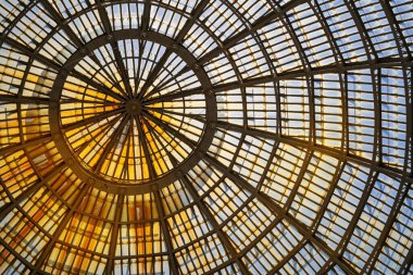 Canlı bir geometrik tasarımın olduğu büyüleyici bir mimari kubbenin yakın çekim görüntüsü. Karmaşık desen, modern mimarinin güzelliğini vurgulayan bir simetri ve merak duygusu yaratıyor..