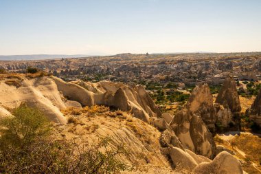 Kapadokya 'nın güzel panoramik manzarası eşsiz kaya oluşumlarını ve engebeli arazisini berrak bir gökyüzü altında sergiliyor. Bu büyüleyici doğal manzara merak ve huşu uyandırıyor..