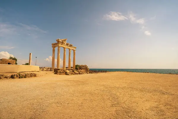 stock image The ancient Temple of Apollo ruins in Side, Turkey, standing majestically by the Mediterranean Sea. The image captures the iconic columns of the temple against a backdrop of a clear blue sky and calm waters, symbolizing the rich history of the region