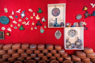 Renkli seramik sanat koleksiyonu, dekoratif tabaklar, ve çarpıcı kırmızı arkaplan üzerindeki çömlek, sanatsal yaratıcılık ve canlı tasarım..