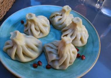 Bir tabak lezzetli Gürcistan hamur tatlısı, khinkali, nar tohumlarıyla servis edilir. Hamur köfteleri ustalıkla katlanmış ve kendilerinden yükselen buhar sıcak ve tatmin edici bir yemek olduğunu gösteriyor..