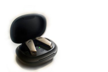 Beyaz bir arka planda izole edilmiş, açık bir şarj çantasında duran, teknoloji ve rahatlık sunan, modern bir çift kablosuz kulaklık. Dijital yaşam tarzı, müzik severler ve sürekli dinlemek için mükemmel..