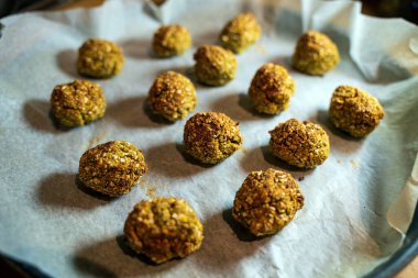 Parşömen kağıdının üzerinde taze pişmiş falafel köfteleri, ev yapımı lezzetli vejetaryen ve vejetaryen atıştırmalık seçenekleri sunuyor. Sağlıklı yemekler ve iştah açıcı yemek sunumları için mükemmel..