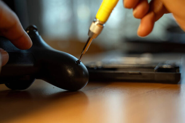 A detailed close-up of a hand using a screwdriver to repair a video game controller, highlighting precision and technical skills. The image conveys themes of gaming, technology, and maintenance.
