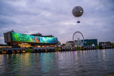 Krakow, Poland - September 25, 2021: A hot air balloon drifts over the Vistula River in Krakow, creating a magical scene with the city skyline illuminated below. The image captures the beauty and charm of the city at night. clipart