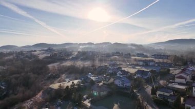 Gün batımında yuvarlanan tepelerin arasına yerleşmiş nefes kesici bir Polonya kasabası manzarası. Güneş ufukta batarken gökyüzü canlı renklerle parlıyor. Polonya, Avrupa