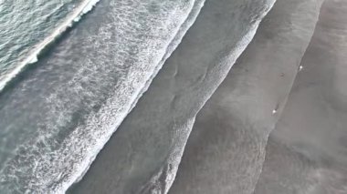 Yumuşak dalgalarla Bali sahilinin havadan görünüşü kumsalda karmaşık desenler yaratıyor, sahil şeridinin doğal güzelliğini ve dingin atmosferini gösteriyor..