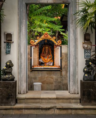 Bali, Endonezya: Tropik geleneksel mimari çerçeveli ve sakin bir ortamda dingin ve ruhani bir atmosferi çağrıştıran, tropikal yeşilliklerle çevrili bir Hindu türbesinin çarpıcı bir görüntüsü.