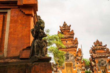 Çok yüzlü çarpıcı bir heykel, Bali Hindu tapınağı girişinde duruyor. Karmaşık oymalar ve canlı renkler sergiliyor. Kültürel zenginlik ve sanatçılık bu ruhani geçitte buluşuyor..