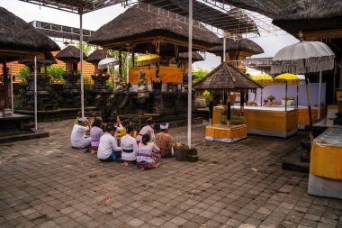 Bali, Endonezya - 29 Kasım 2023: Süslü mimari ile çevrili geleneksel bir Bali tapınağında dindarların yer aldığı sakin bir sahne